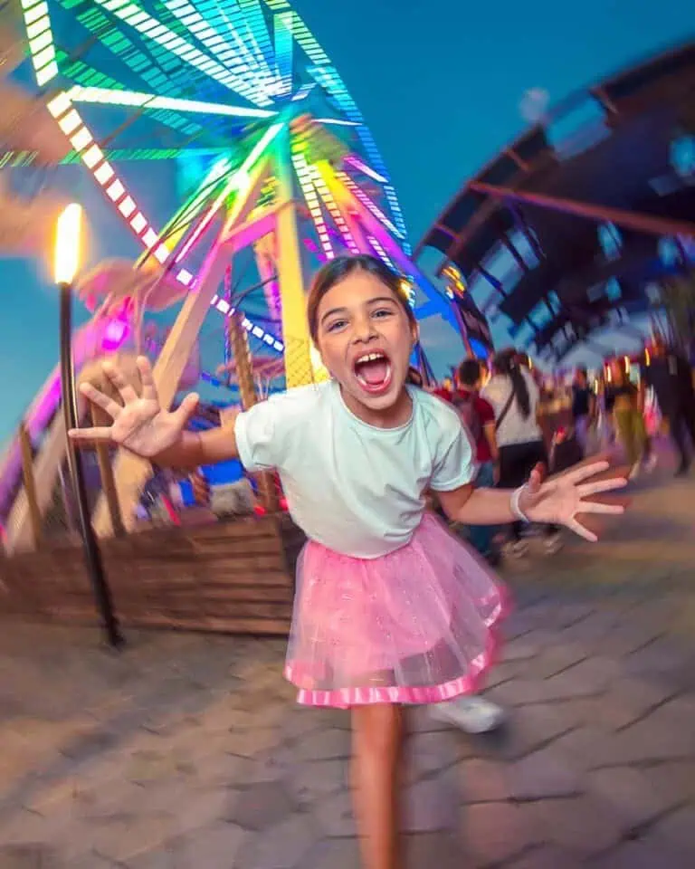 Children's amusement park rides with illuminated Ferris wheels and children enjoying a family event. Colorful image of an amusement park at night with children playing and vibrant lights.
