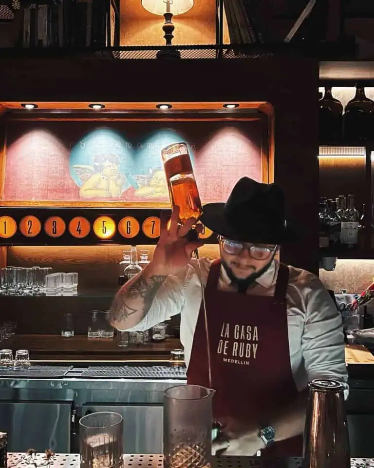 鸡尾酒吧，调酒师手持一杯酒，酒吧采用现代装饰风格，并带有木质细节。