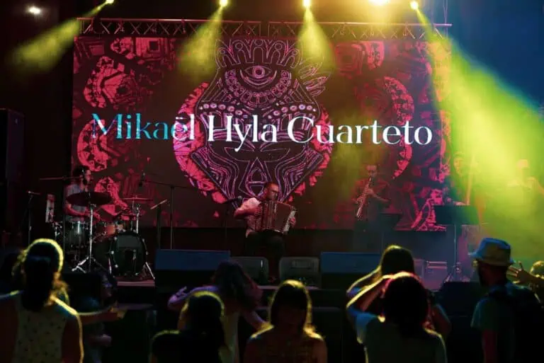 米凯尔·泰拉四重奏现场音乐会，舞台灯光璀璨，乐队在节日或文化活动中演奏乐器，营造出喜庆而富有艺术气息的氛围。