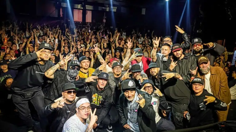 一群艺术家和观众在现场音乐会上，气氛热烈，灯光闪烁，充满活力，旨在推广哥伦比亚的文化和音乐活动。