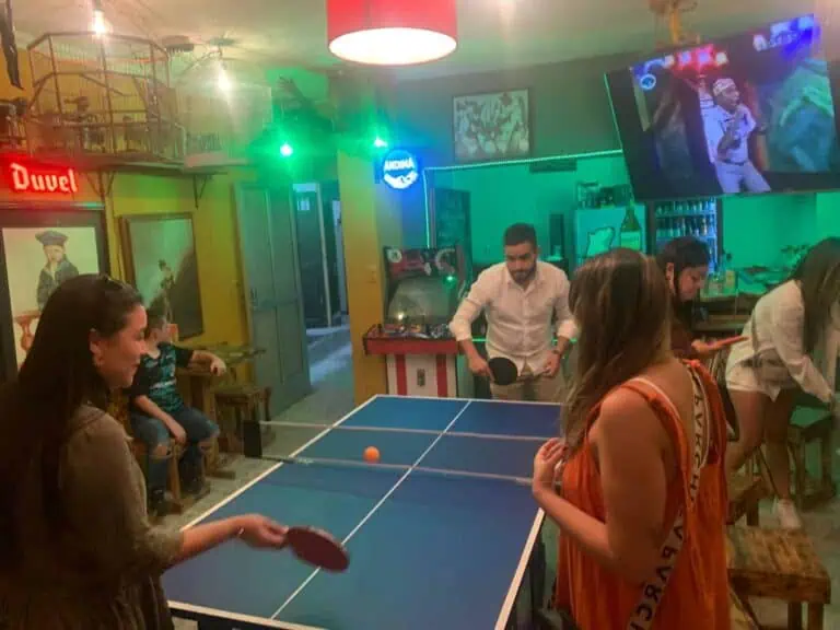 Genießen Sie eine Partie Tischtennis in festlicher Atmosphäre mit stimmungsvoller Beleuchtung in einer Bar oder einem Veranstaltungsort. Treffen Sie sich mit Freunden in einem farbenfrohen und lebendigen Raum.