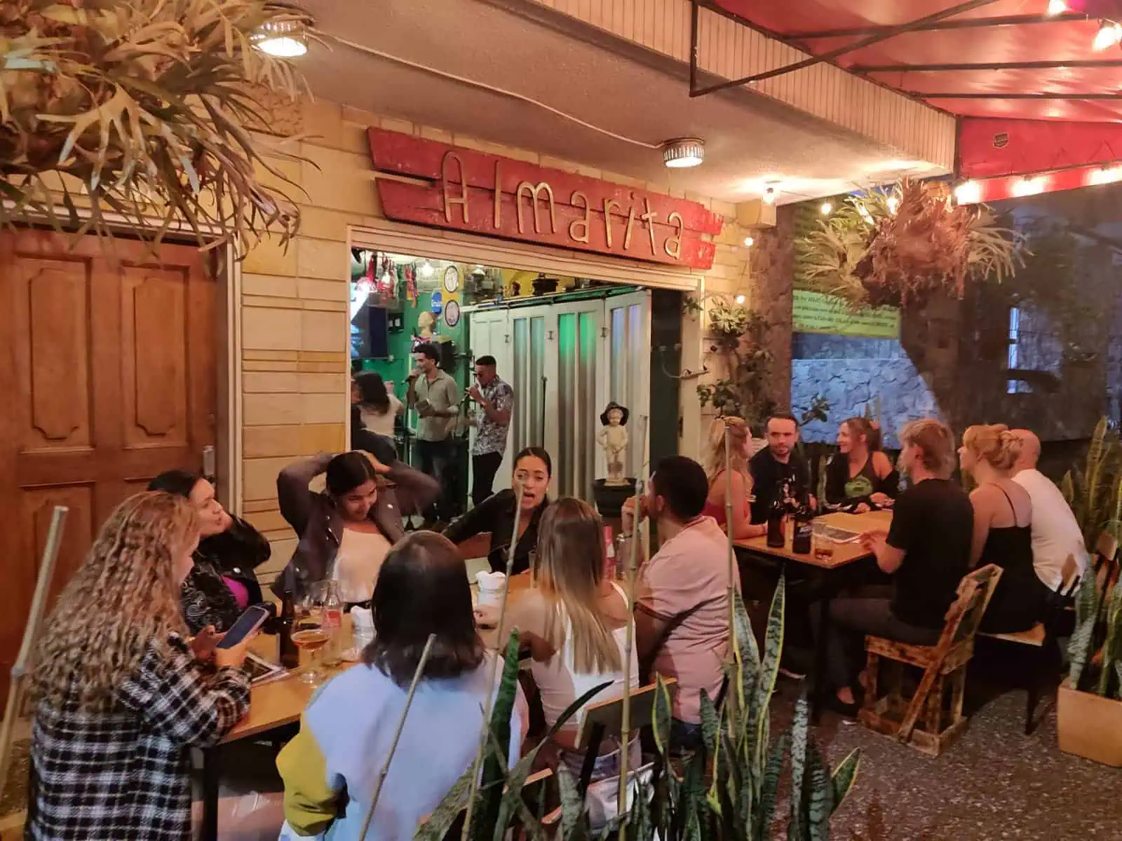 Tables with friends in a restaurant with a festive atmosphere and vibrant decorations. People enjoying food and drinks in an outdoor space that evokes conviviality and joy.