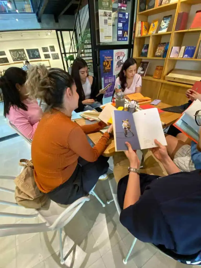 Des livres et des lecteurs dans une librairie ou un espace de lecture, montrant un environnement d'apprentissage et culturel, avec des personnes lisant et partageant des livres et des événements littéraires.