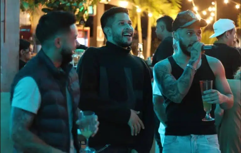 在哥伦比亚波哥大，一场社交活动中，朋友们在露天酒吧里畅饮，享受夜晚的狂欢节，温暖的灯光和现场音乐营造出喜庆欢乐的气氛，这是一场社交娱乐活动。