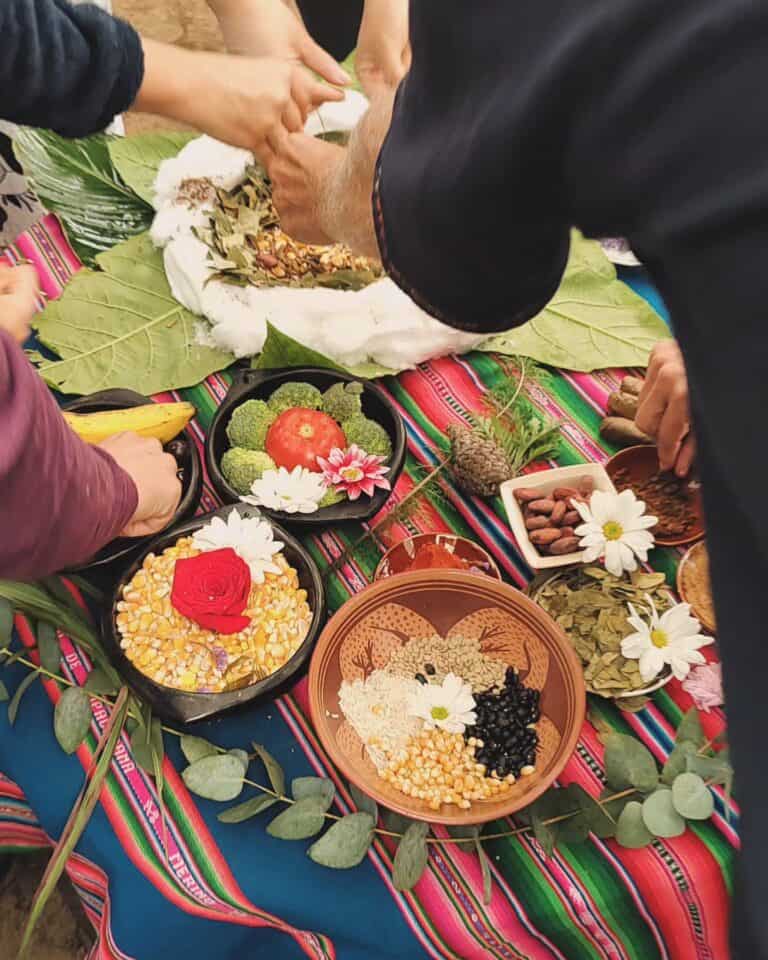 Cena de ofrenda tradicional colombiana con flores, frutas y elementos culturales en un tapete colorido.