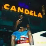 在哥伦比亚的一场娱乐活动中，一名戴着墨镜、身穿黑色T恤的年轻男子，身着休闲装坐在车里，在夜色背景下，醒目的Canadela标志映入眼帘。