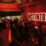 Eventario室内社交活动，红灯闪烁，气氛活跃，是现代社交和娱乐的庆典场所，空间装饰充满都市气息，霓虹灯字母 INSTINTO，人们互动交流，氛围充满活力和友好，活动场地位于波哥大。