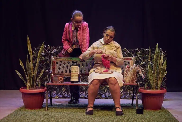 Schöne Frauen auf einer Theaterbühne mit dekorativen Pflanzen und Vintage-Accessoires.