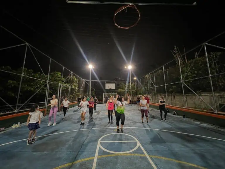 Des joueuses de basket-ball s'entraînent sur un terrain extérieur la nuit, projecteurs, activités sportives, événement sportif organisé par Eventario.