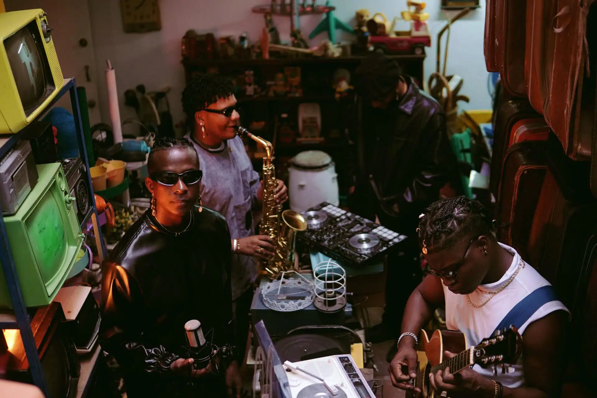 Des gens jouent des instruments lors d'un événement musical, avec du matériel de DJ, des guitares et de la technologie dans un environnement dynamique et énergique.