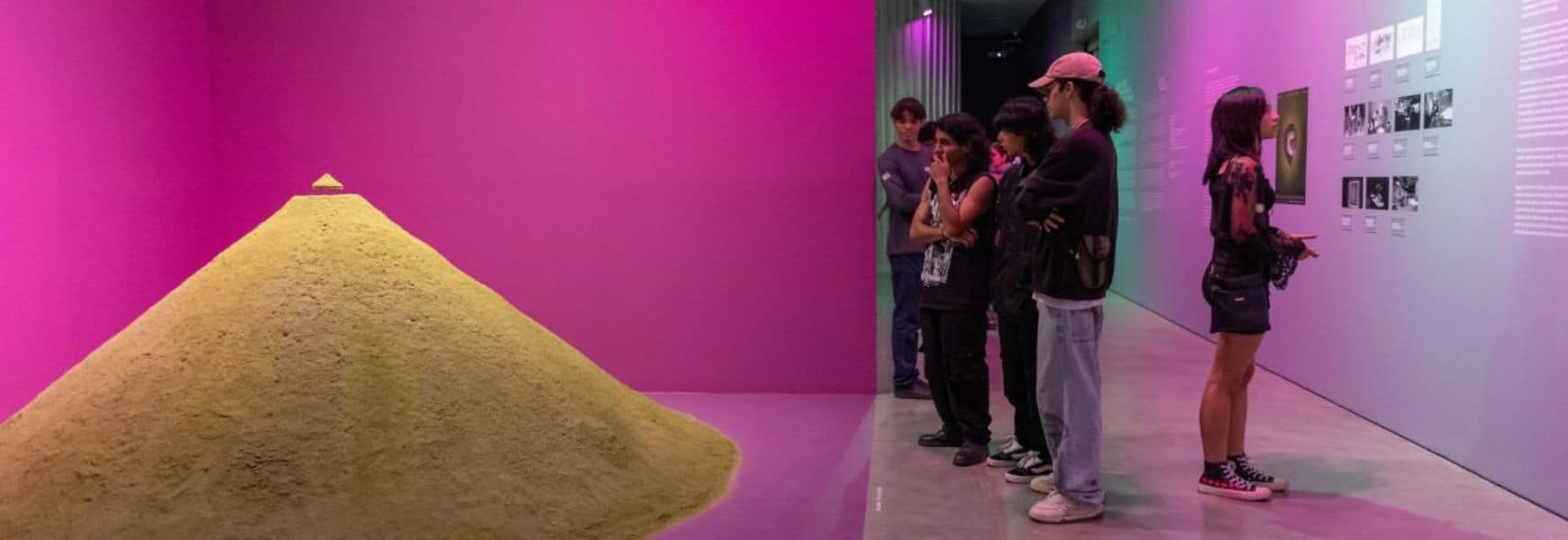 Montículo de arena en una exhibición artística con luces de neón en un museo de arte contemporáneo.