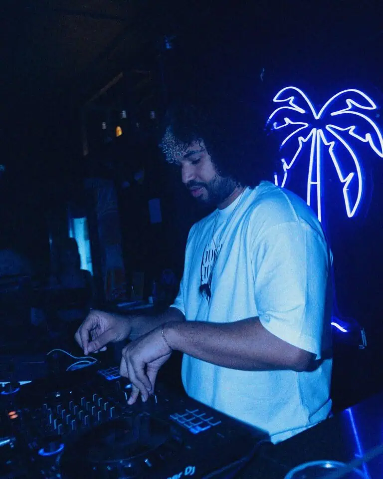 DJ lors d'un événement à Bogotá, avec éclairage néons sous les palmiers, musique live et ambiance festive et jeune. Idéal pour promouvoir les soirées et la vie nocturne colombienne.