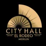 一个游乐场景点，以黑色背景上的金色旋转木马为特色，宣传麦德林市政厅 El Rodeo，专注于麦德林市的活动、娱乐和文化。