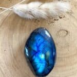 Lápiz con pluma blanca y piedra de lapislázuli sobre superficie de madera natural.