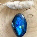 Lápiz con pluma blanca y piedra de lapislázuli sobre superficie de madera natural.