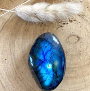 Lápiz con pluma blanca y piedra de lapislázuli sobre superficie de madera natural.