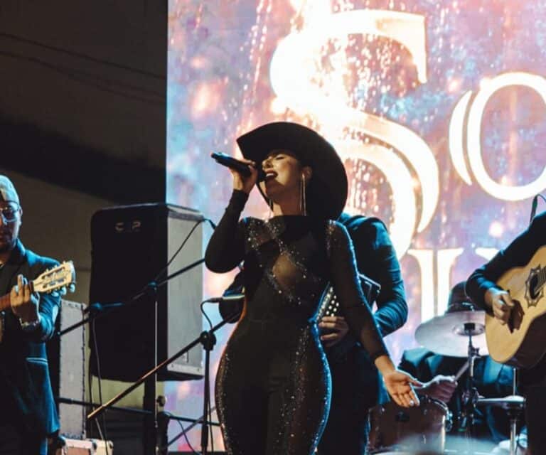 Cropped image of a female singer performing at a live music event with a backdrop displaying "50" at a concert in Colombia.