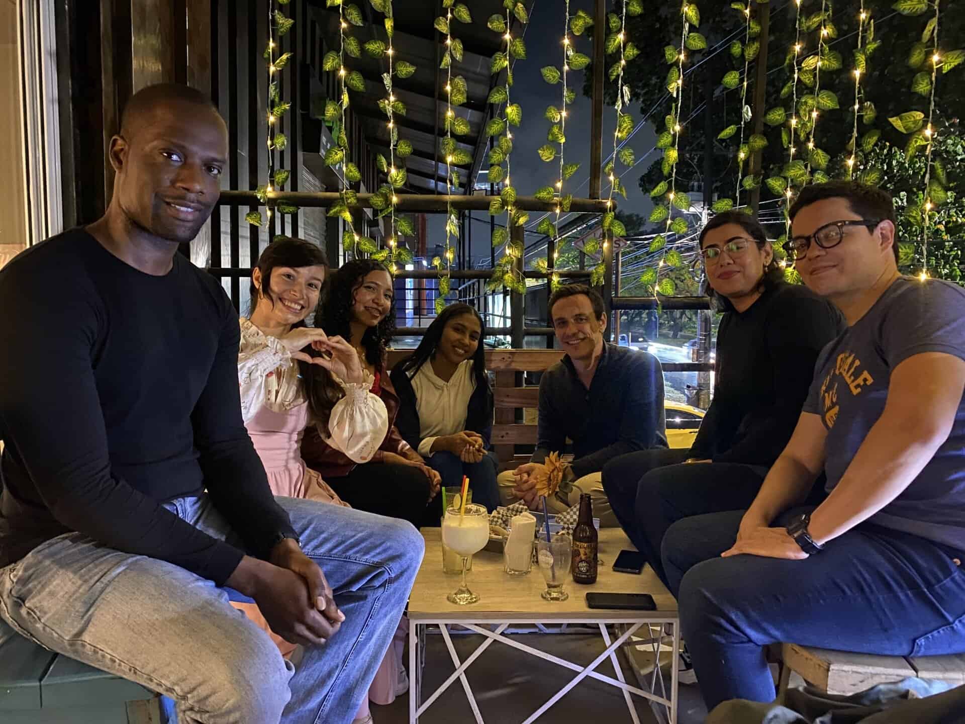 Disfrutando en evento social al aire libre en un restaurante con ambiente acogedor y decoración de luces, promoviendo networking y momentos memorables con amigos y colegas.