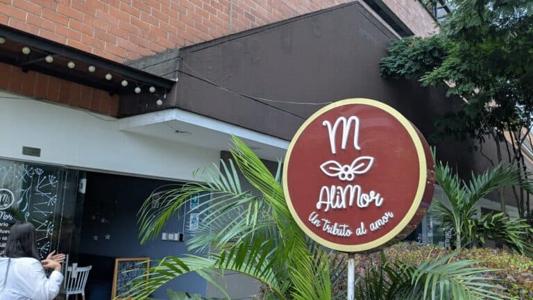 Jardín con señal de restaurante "Mi Amor" en exterior, decoración con plantas tropicales y ambiente acogedor para eventos y celebraciones románticas.
