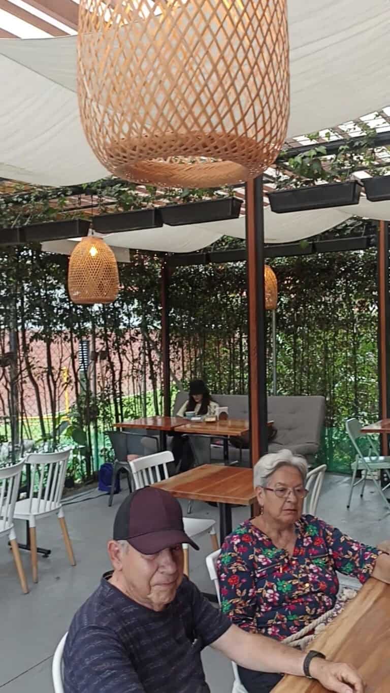 Belleza de espacio al aire libre en un restaurante con decoración moderna y encantadora, mesas de madera y faroles de mimbre para eventos y reuniones.