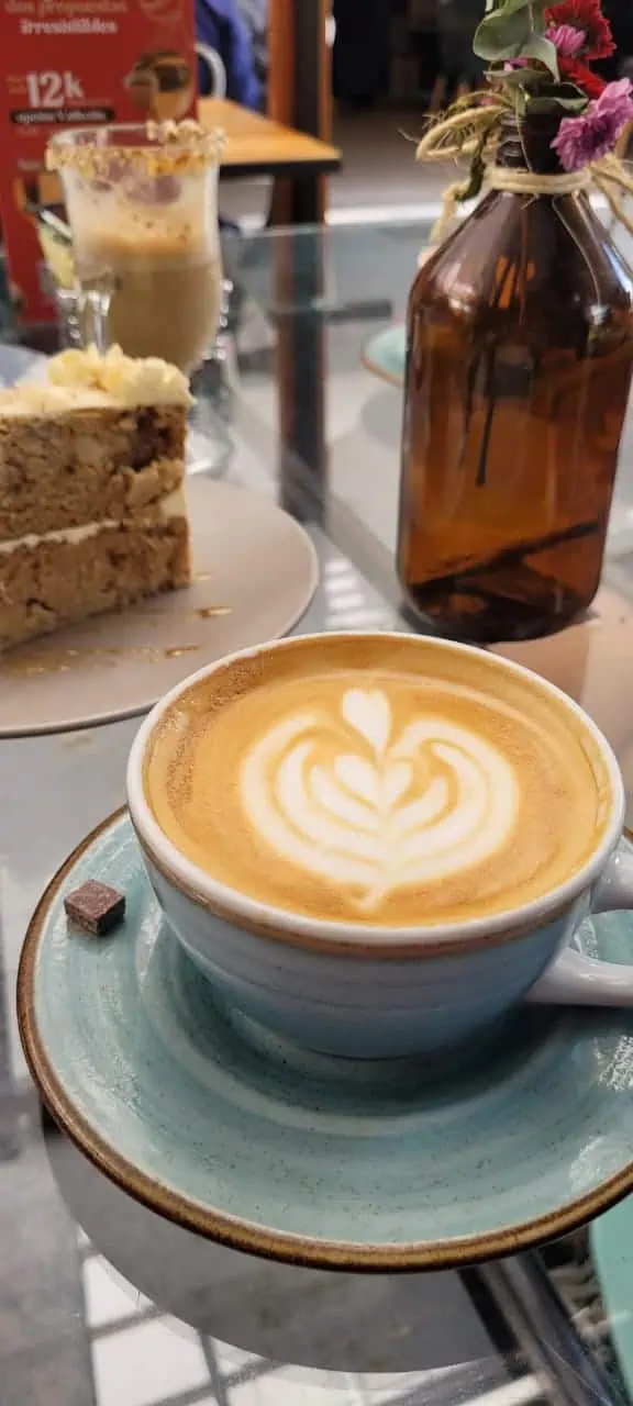 Kaffee mit Latte Art und Kuchen in einem gemütlichen Café in Bogotá. Das Foto zeigt die perfekte Atmosphäre für einen Moment der Entspannung und des Geschmacks.