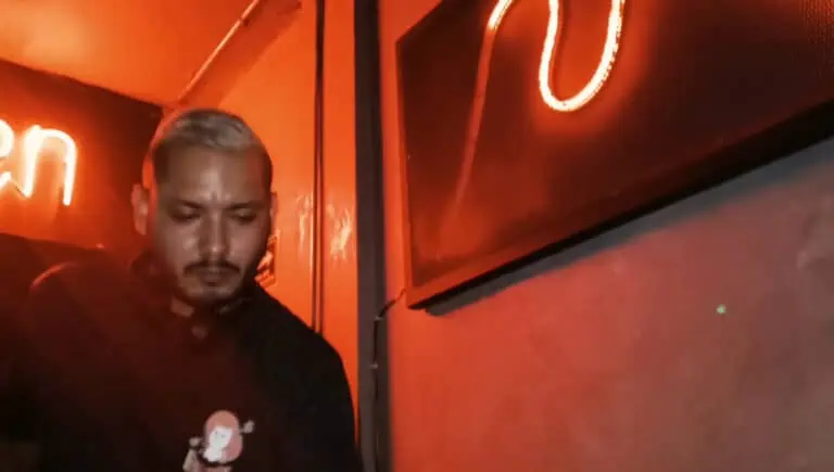 Event decor in red tones with neon lighting, featuring a focused man in the background, a modern, urban atmosphere, ideal for promoting events and social gatherings in Medellín.