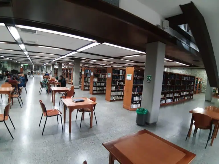 Une bibliothèque publique moderne avec des tables et des étagères remplies de livres, des étudiants lisant et travaillant, et un environnement calme pour étudier et apprendre. Idéale pour ceux qui recherchent des ressources académiques dans une bibliothèque moderne.