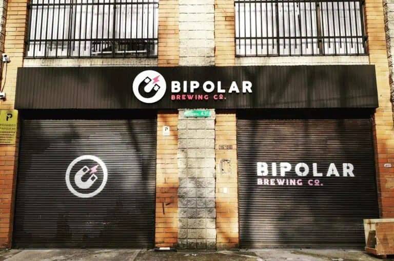 Bipolar Brewing Co. 的店面位于城市街道上，正面有标志和名称，配有深色金属锁，街角还有一个招牌。