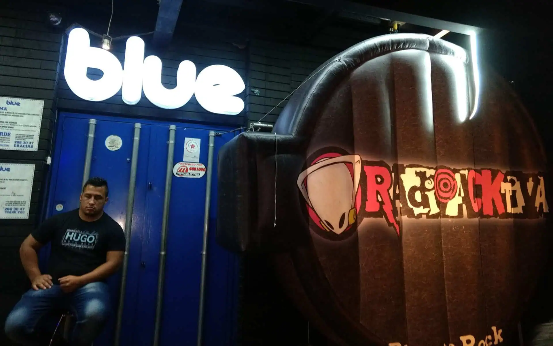 Bleu, un logo d'ambiance événementielle et de bar, mettant en scène une personne assise et des éléments décoratifs dans une boîte de nuit à Bogotá.