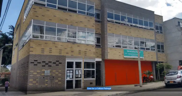 Bâtiment moderne à plusieurs étages avec de grandes fenêtres et un panneau "Casa de Culture Pedregal" sur la façade.