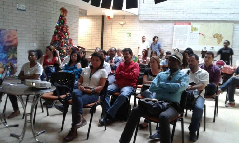 Audiencia en evento de capacitación o conferencia en interior de edificio con decoración navideña en Colombia.