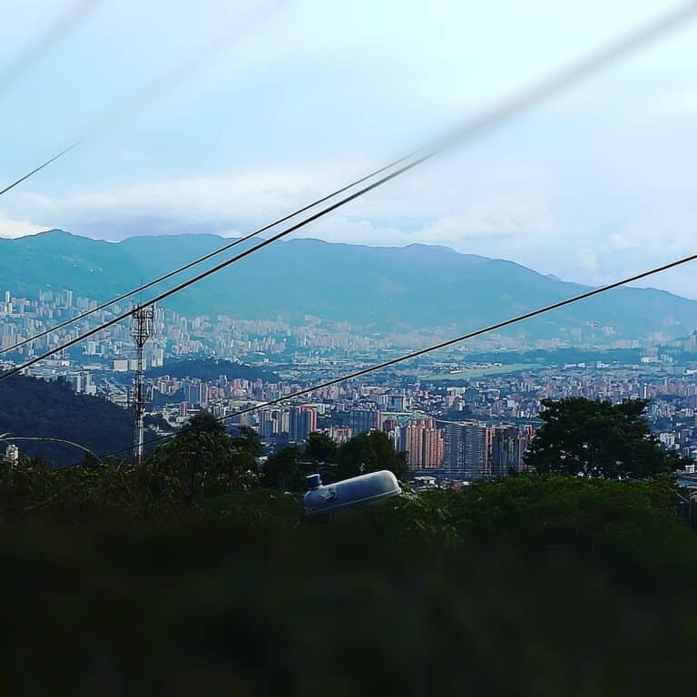 Vistas panorámicas de Medellín desde una zona elevada con cables de transporte, mostrando una ciudad moderna rodeada de montañas y naturaleza, ideal para eventos y turismo en Colombia.
