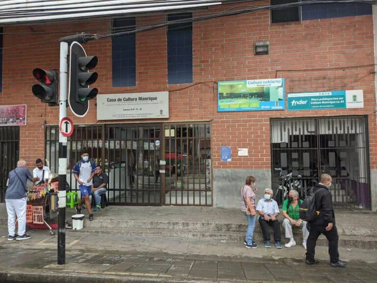Centres culturels et espaces communautaires à Medellín, dans la rue 45, dans un cadre urbain avec des personnes portant des masques, attendant et socialisant, reflétant la vie quotidienne de la ville.