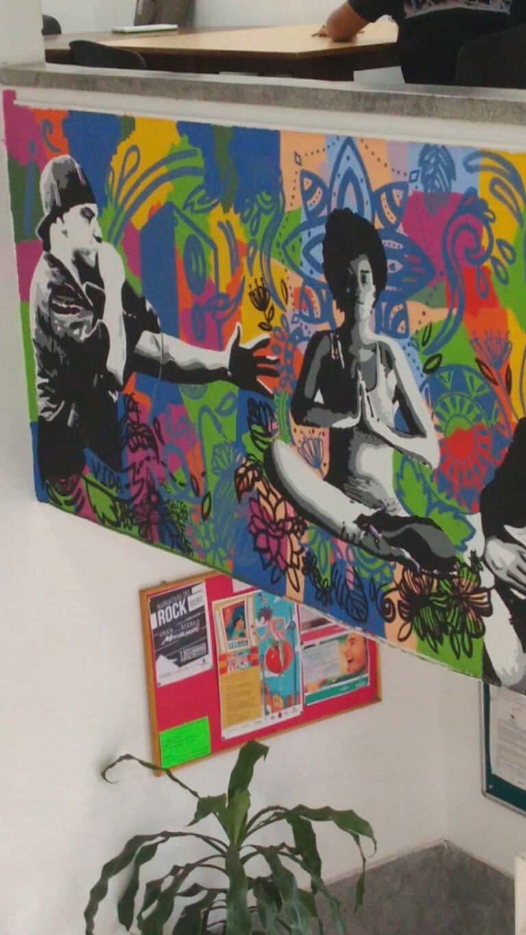 Arte mural colorido con figuras humanas y fondo floral vibrante en una sala de eventos.