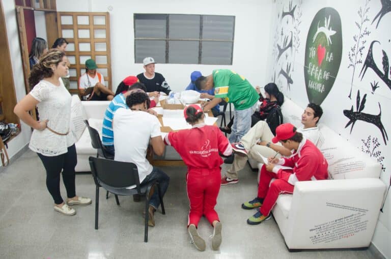 Eventos de capacitación y talleres participativos con jóvenes en un espacio interior de estilo moderno en Colombia. La imagen muestra a varios asistentes en actividad, promoviendo la lectura y el aprendizaje.