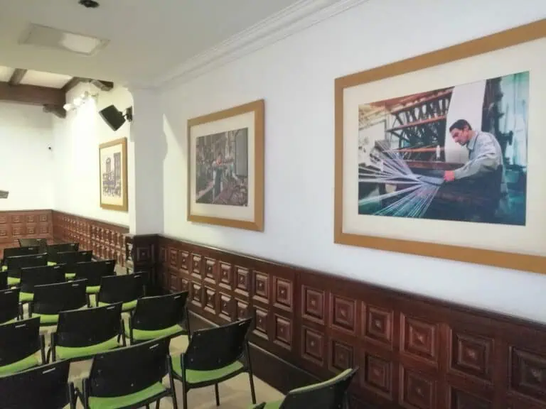 参加商务活动或会议的人员，活动场地墙壁上装饰着画作，椅子颜色各异。