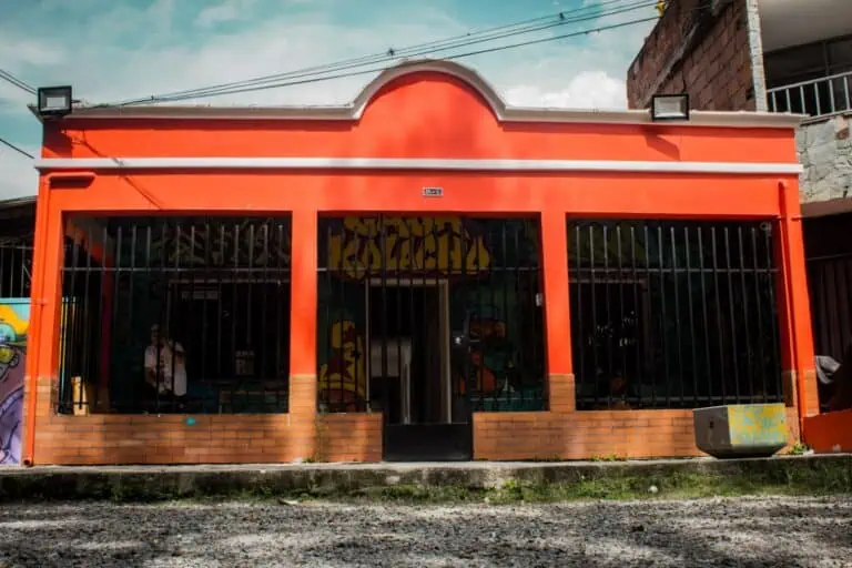 Farbenfrohe Geschäftsfassade in Bogotá mit Graffiti-Wandmalereien und einer Eisenkonstruktion, die urbane Kunst und lokale Kultur hervorhebt.