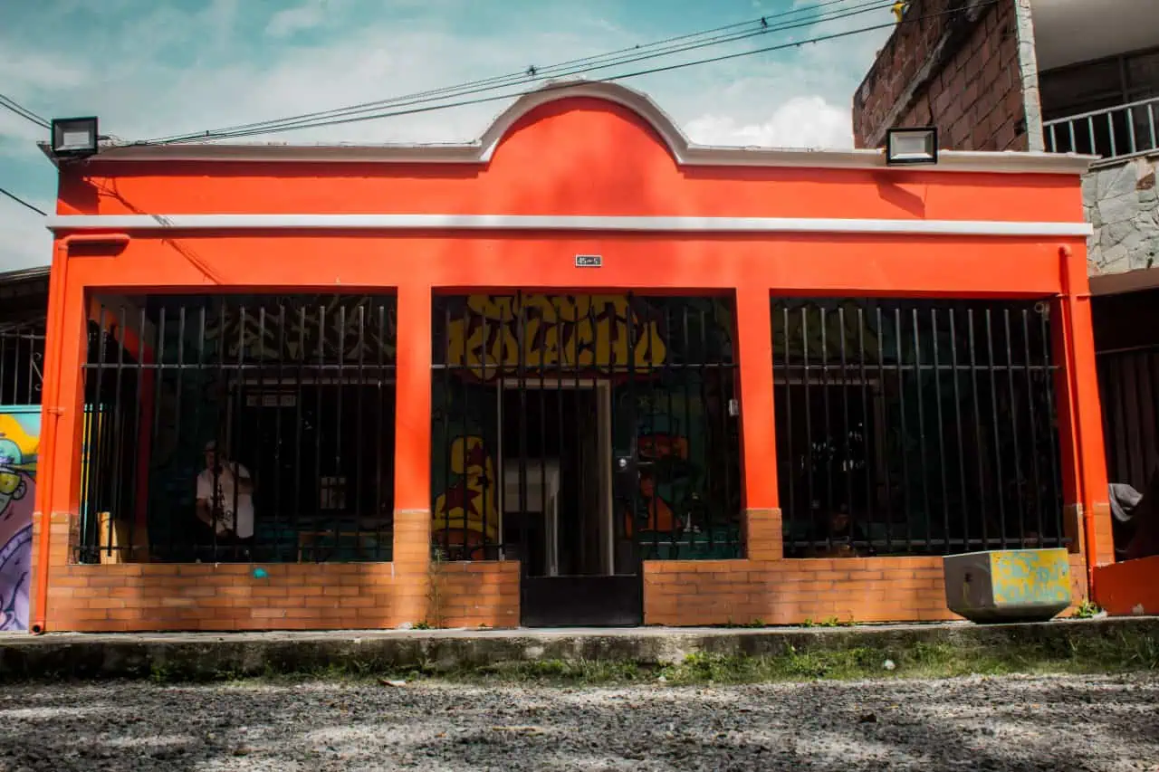 Farbenfrohe Geschäftsfassade in Bogotá mit Graffiti-Wandmalereien und einer Eisenkonstruktion, die urbane Kunst und lokale Kultur hervorhebt.