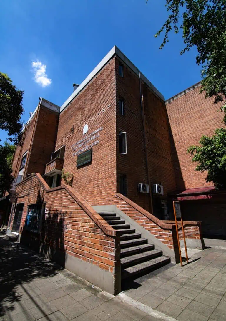 波哥大人类学与文化研究所大楼，红砖外墙，正面有楼梯，晴天时天空晴朗。