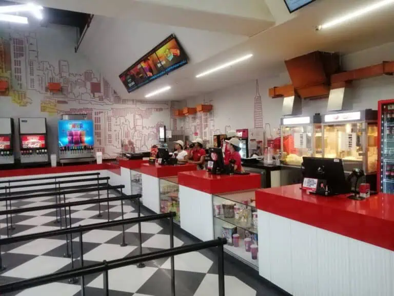 快餐店设有收银机，员工戴着帽子，背景是城市壁画，屏幕上播放着促销信息，环境干净现代，适合举办活动和提供客户服务。