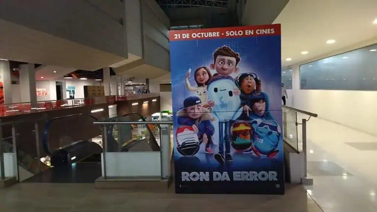 Werbebanner für den Kinostart des Films „Ron da Error“, das in einem Einkaufszentrum in Kolumbien angezeigt wird und animierte Figuren und das Erscheinungsdatum zeigt.
