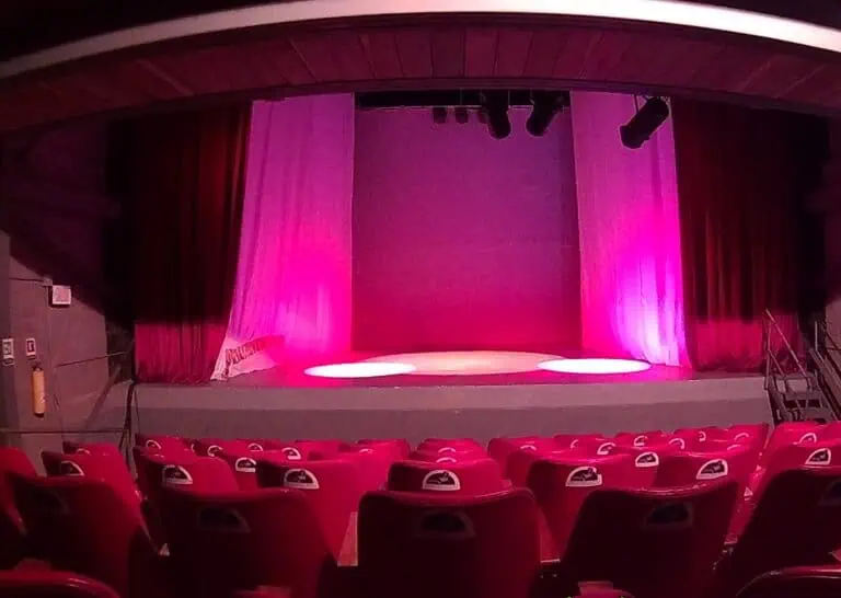 Lumières et rideaux sur une scène de théâtre, installés pour des événements et des spectacles dans une salle couverte.