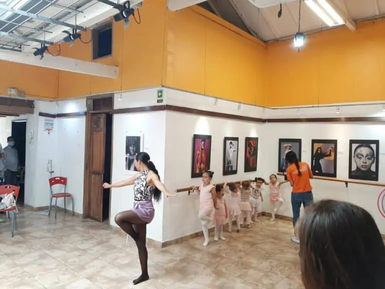 Dancers and children participating in an art activity at a children's art gallery in an interior space decorated with framed artwork.