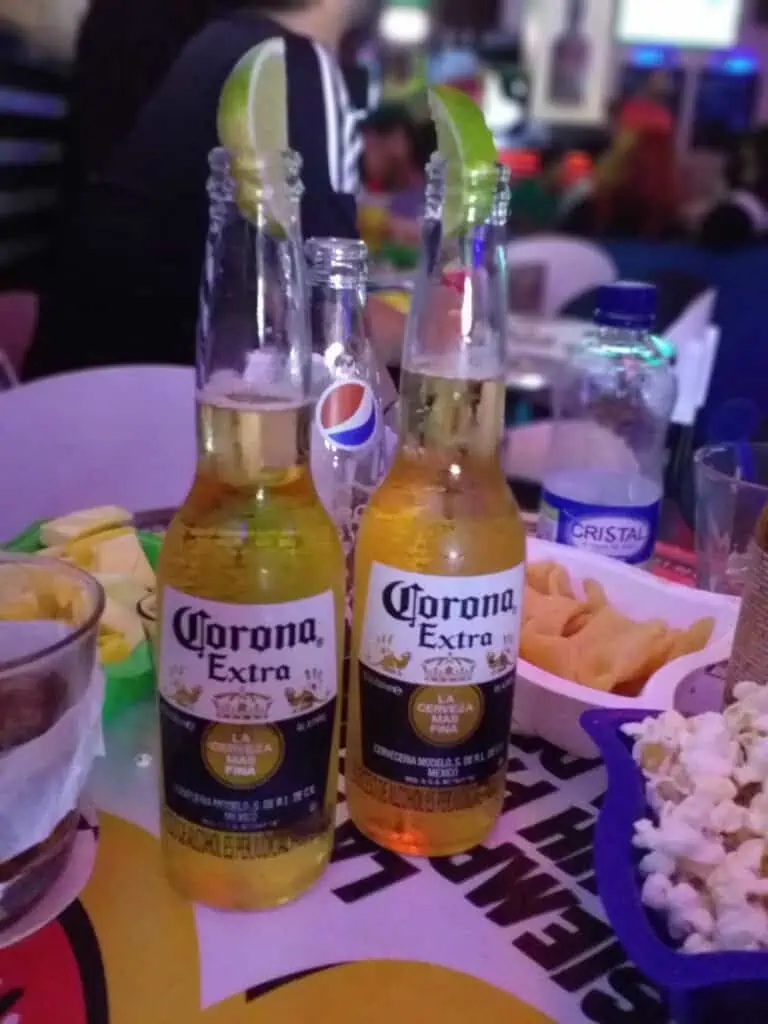 Bottles of Corona Extra beer on a table with snacks at a social event.