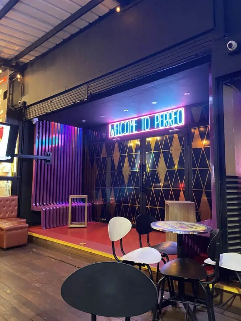 Welcome to Perreo neon sign coffee shop with modern decor, colorful lighting, and trendy seating, perfect for socializing and enjoying vibrant nightlife.