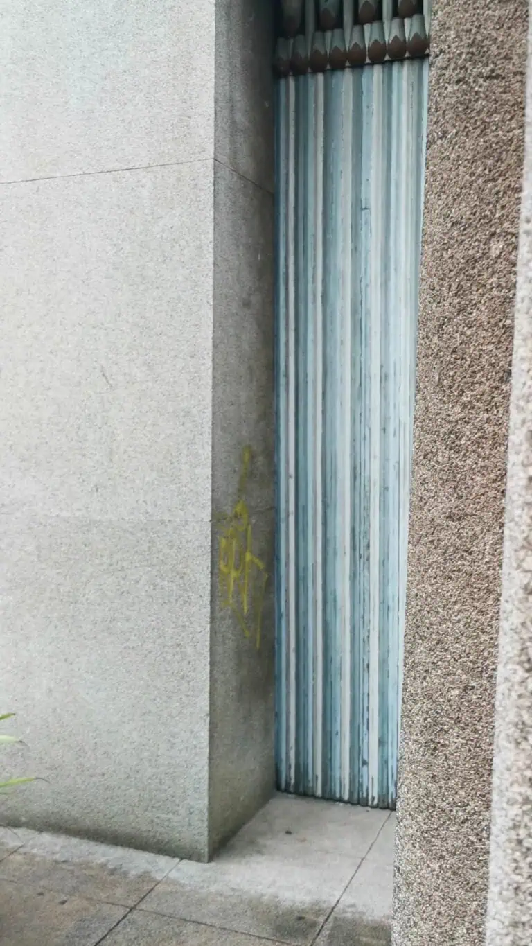Blue-painted metal roll-up door on a concrete and stone wall exterior.