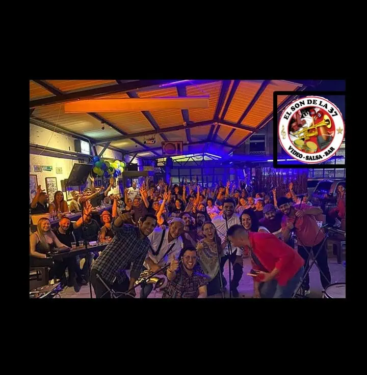 El Son de la 31 酒吧热闹非凡，现场音乐、舞蹈和欢乐气氛弥漫。顾客们在充满活力的空间里享受着社交活动、萨尔萨舞表演和酒吧服务，气氛十分欢乐。