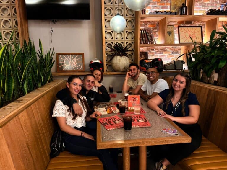 Disfrutando una comida en grupo en un restaurante moderno con decoración de ladrillos expuestos y plantas verdes, ideal para eventos sociales y reuniones con amigos.