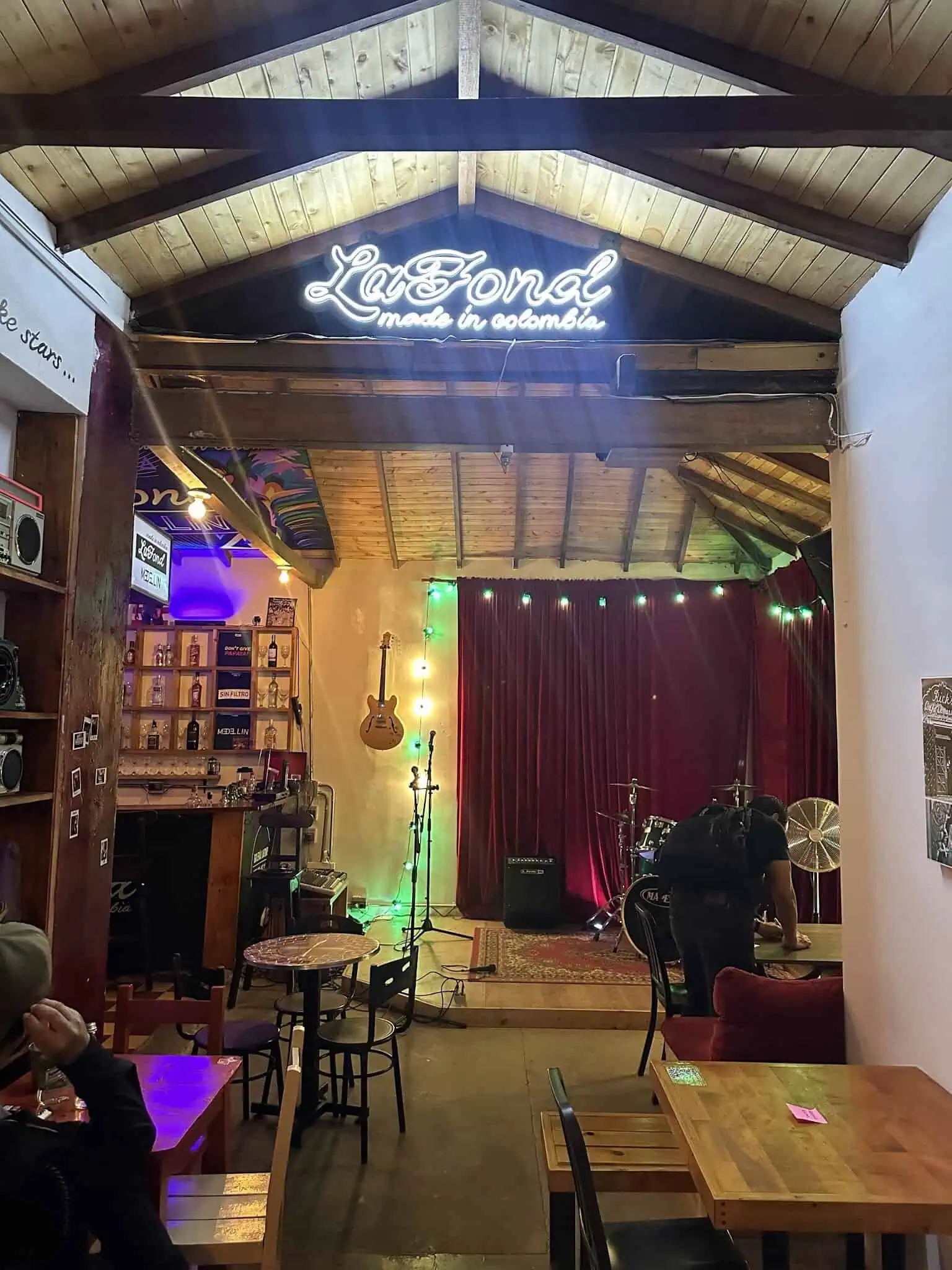 Un panneau lumineux indiquant « La Fond música en Bogotá » au plafond d'une salle avec une scène musicale et un décor coloré.