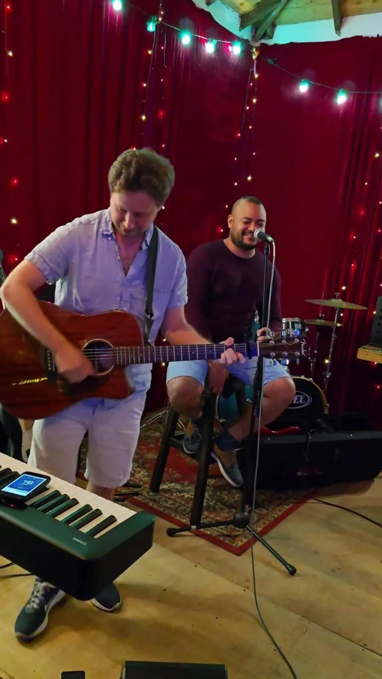 Arts musicaux lors d'un événement social, avec des musiciens jouant de la guitare et chantant en direct, une ambiance festive avec des lumières décoratives, du son et des divertissements, un événement en salle avec une scène chaleureuse.